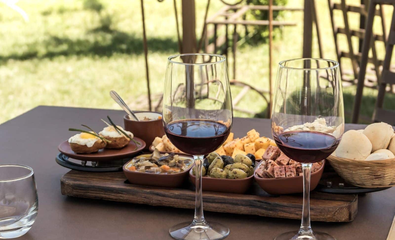 Red wine glasses paired with a tasting board of cheese, olives, and bites during a Galena Wine Tours stop.