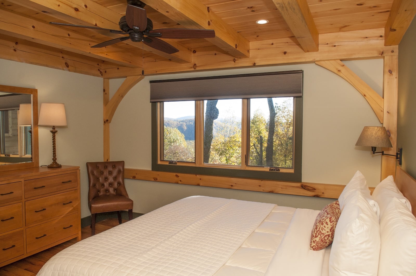 A guest suite, featuring a bed and dresser with a window with mountain vies at a Bed and Breakfast in NC.