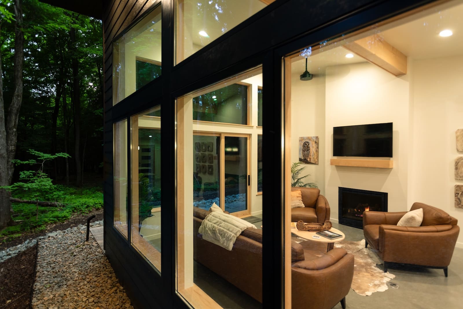 A view of a living room through large windows with surrounding woods at one of the most romantic secluded cabins in Wisconsin.