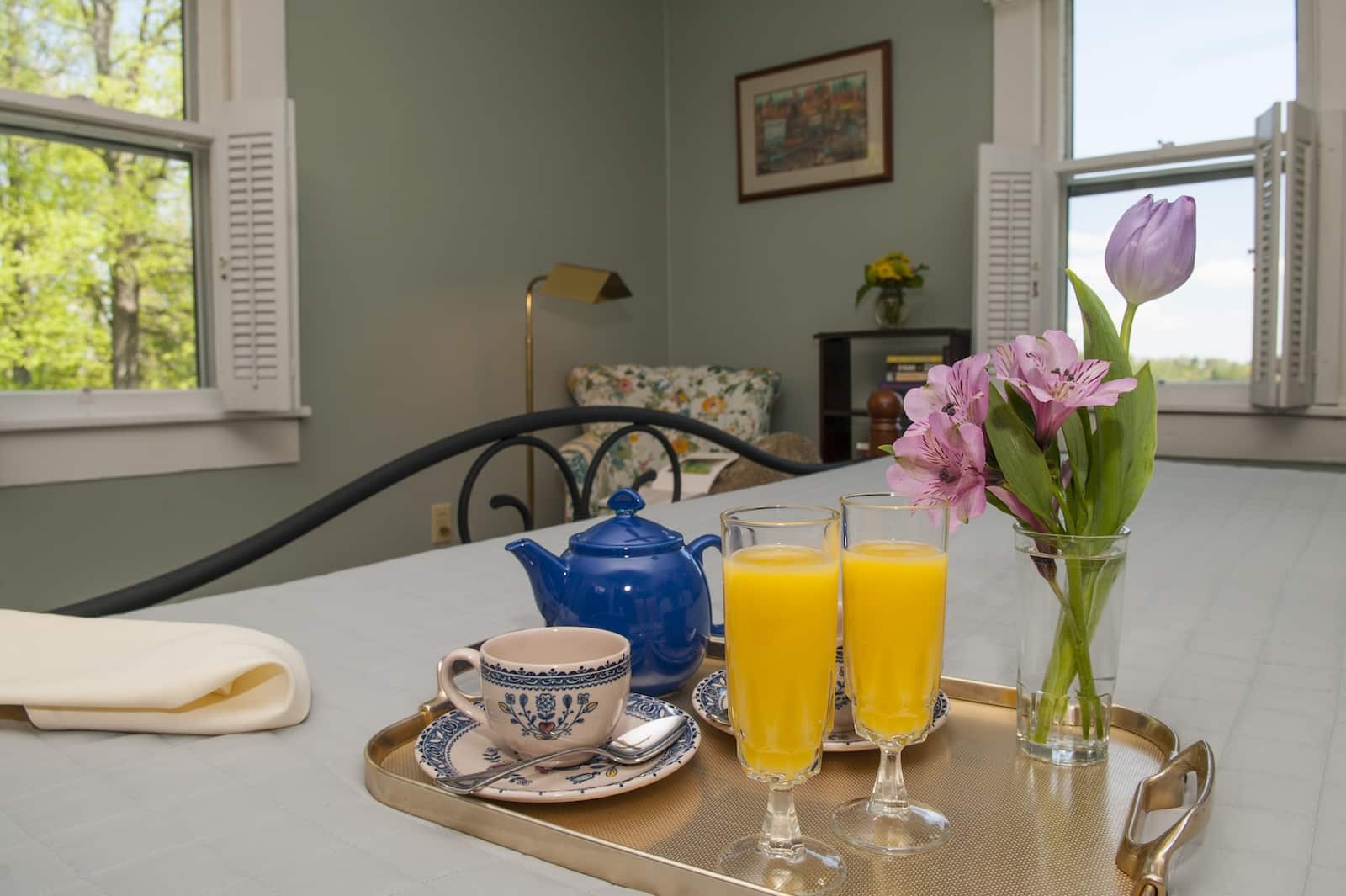 A tray with juice, tea, and flowers on a bed at a bed and breakfast Saluda NC.