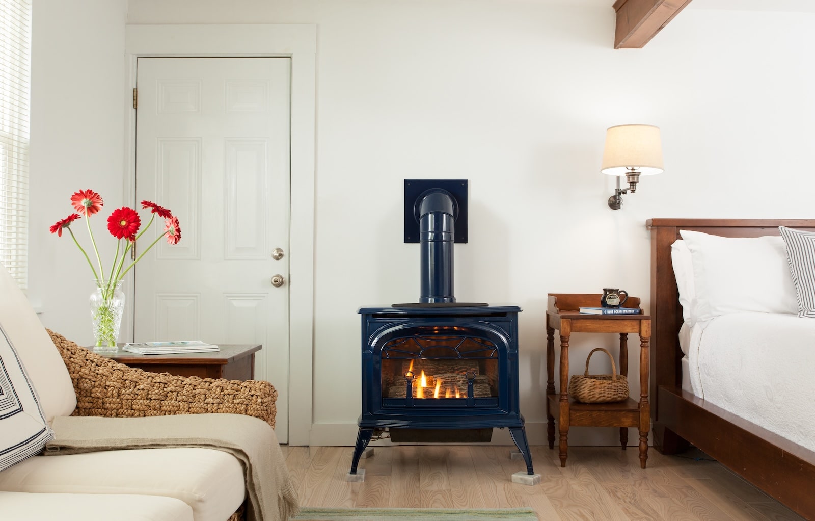 A guest room with flowers, a fireplace, a seating area, and a bed at a Bed and Breakfast in New Hampshire.