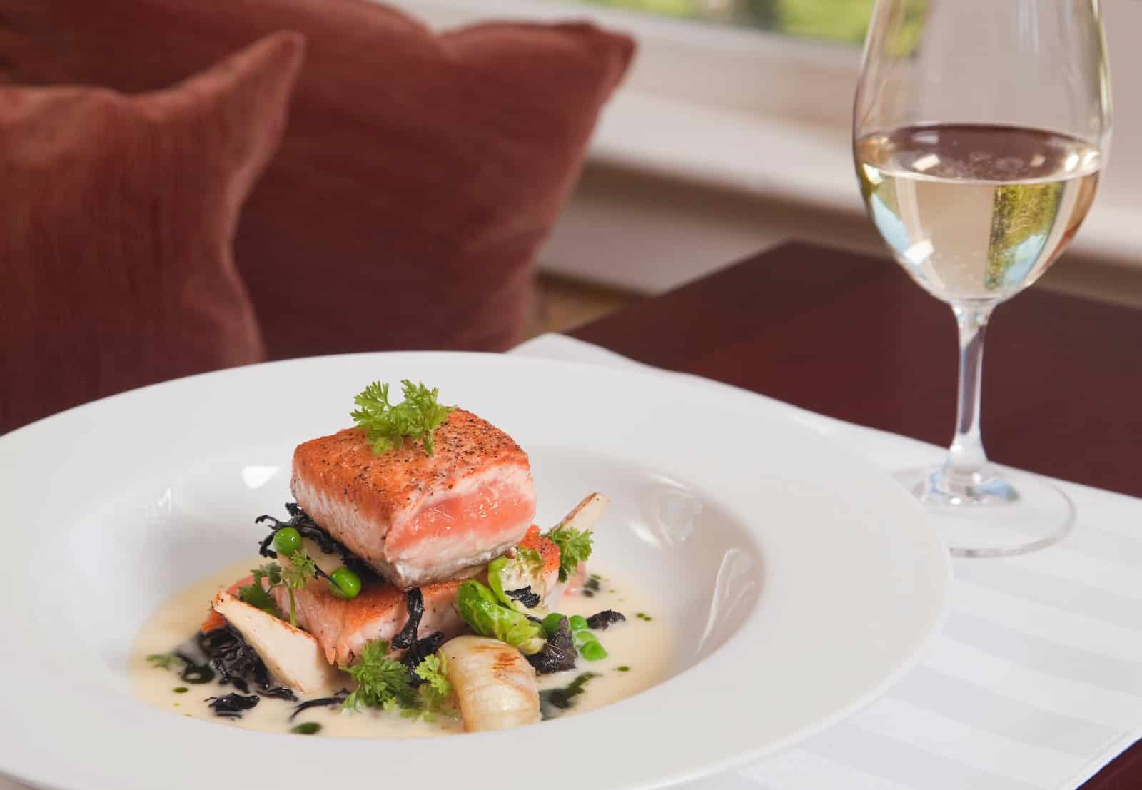A plate of salmon and a glass of wine at a fine dining restaurant at a Bed and Breakfast in New Hampshire.