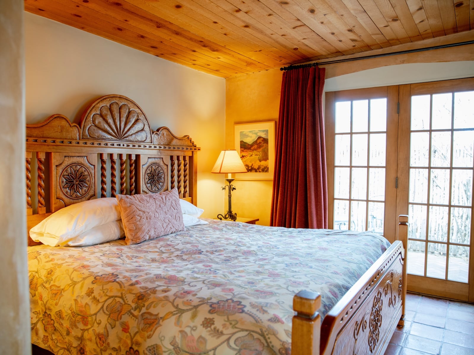 A bed by a lamp and windows at a Bed and Breakfast in Santa Fe.