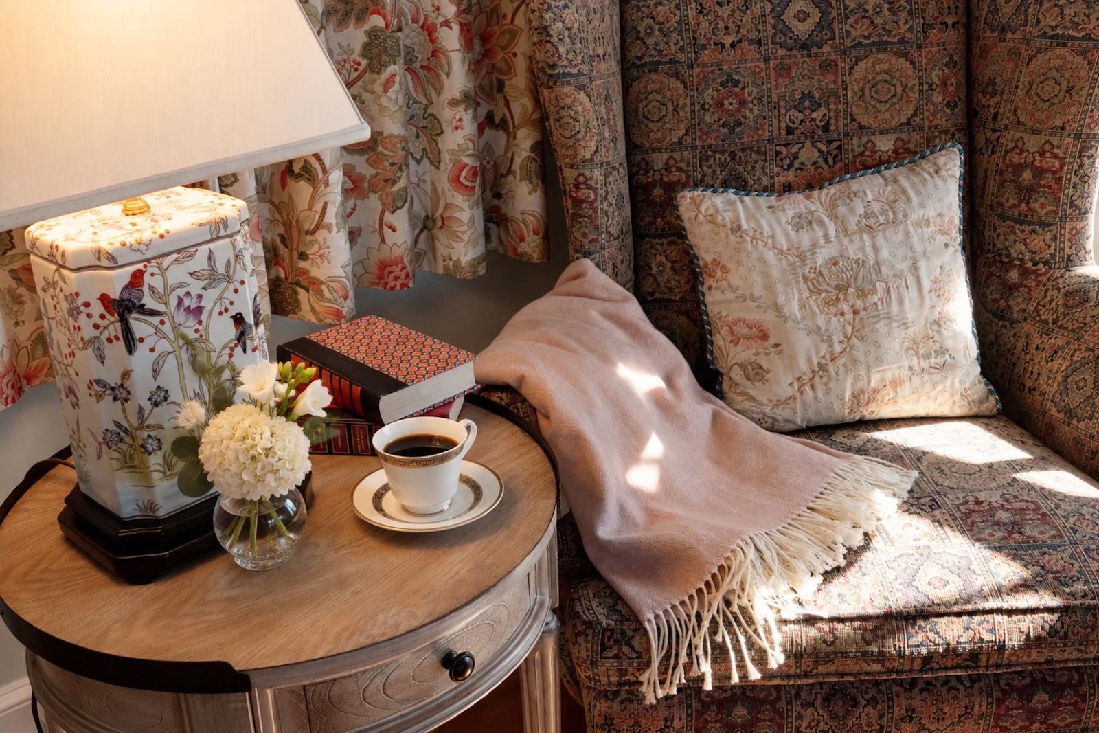 A chair with a blanket by a side table with coffee and lamp, a cozy setting in one of the best Exeter hotels.