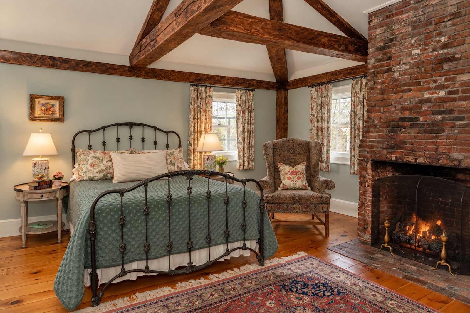 A queen bed by a lamp and a chair with a fireplace in a guest room at one of the bet hotels in Exeter NH.