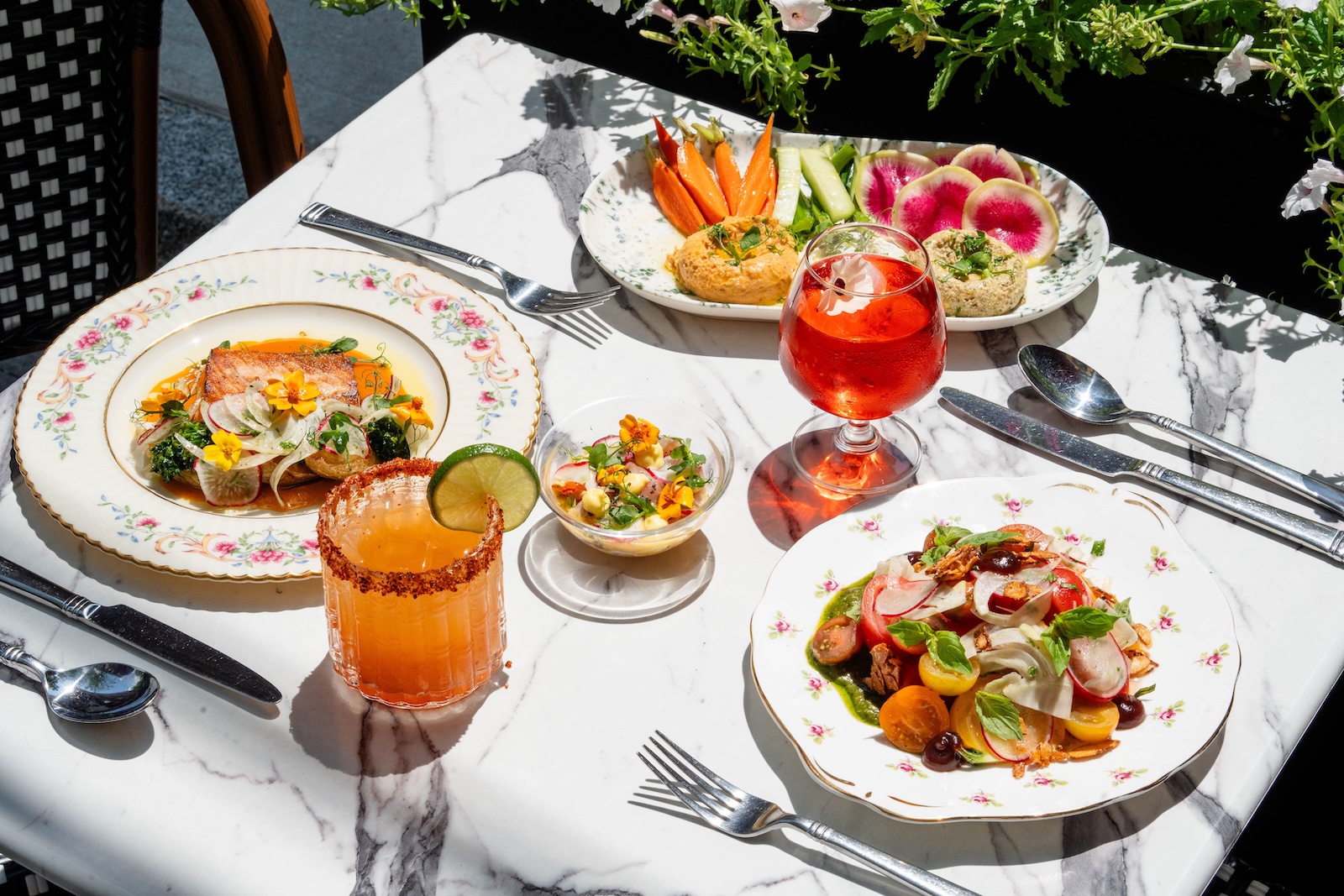 A spread of dinner and drinks on a white table at Ambrose Restaurant inside one of the best Exeter hotels.