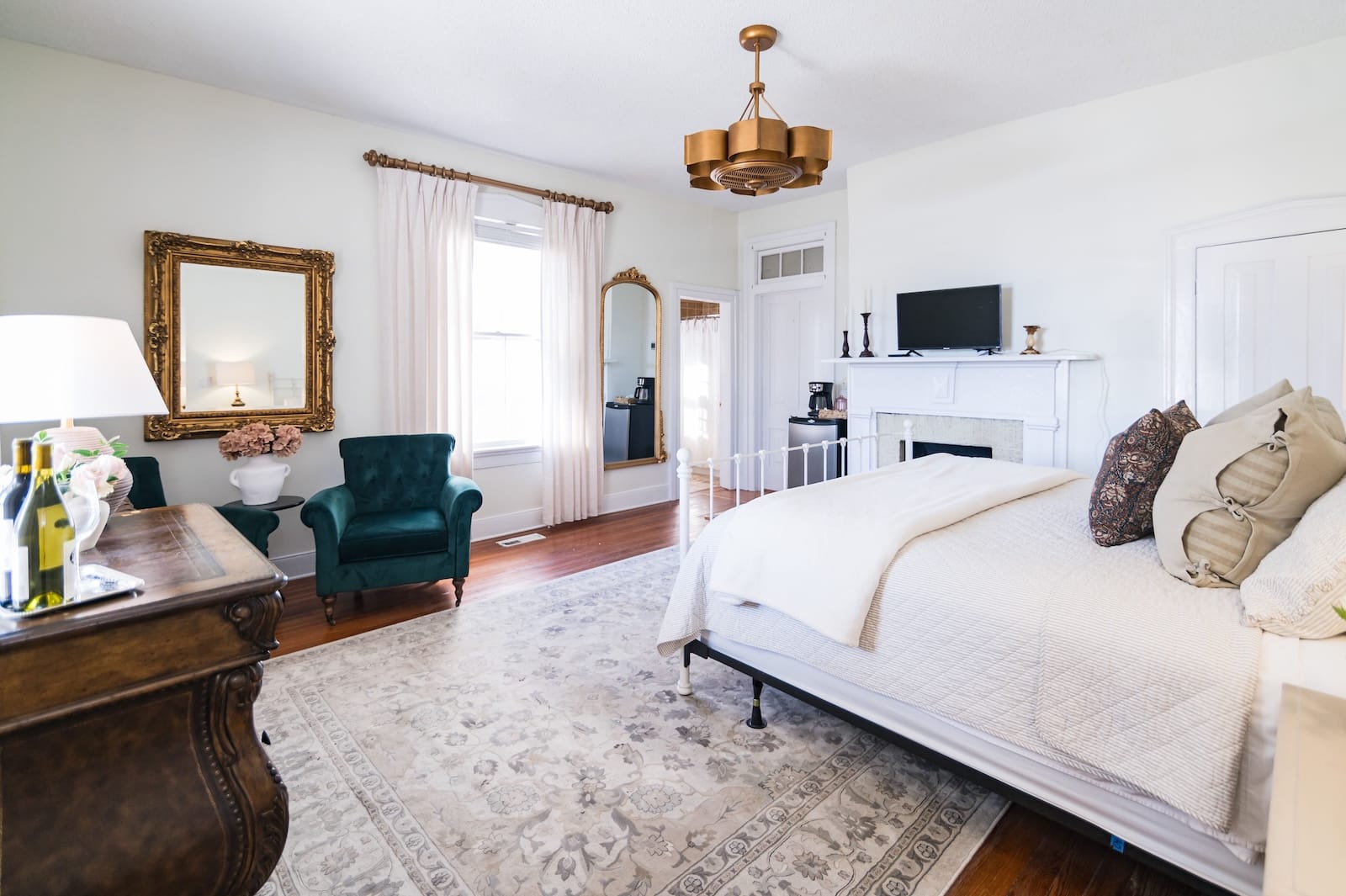 A guest room with a bed, dresser, mirror, and fireplace at a Charlottesville bed and breakfast.