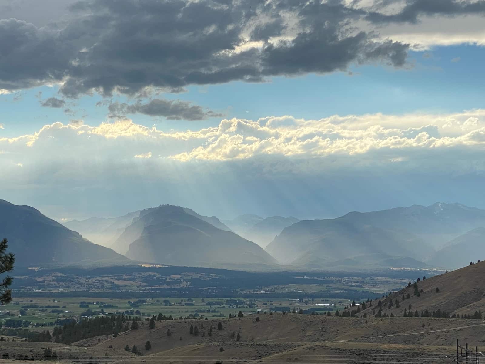The Bitterroot Valley in Montana, one of the Yellowstone filming locations, with mountains and the sun shining through clouds.