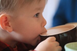Close up photo of toddler sipping from a cup of hot coca on the Durango Polar Express