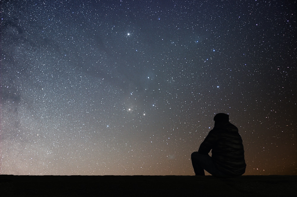 Man looking at a dark sky, like what you'll find at the stunning Valles Caldera National Preserve in Santa Fe