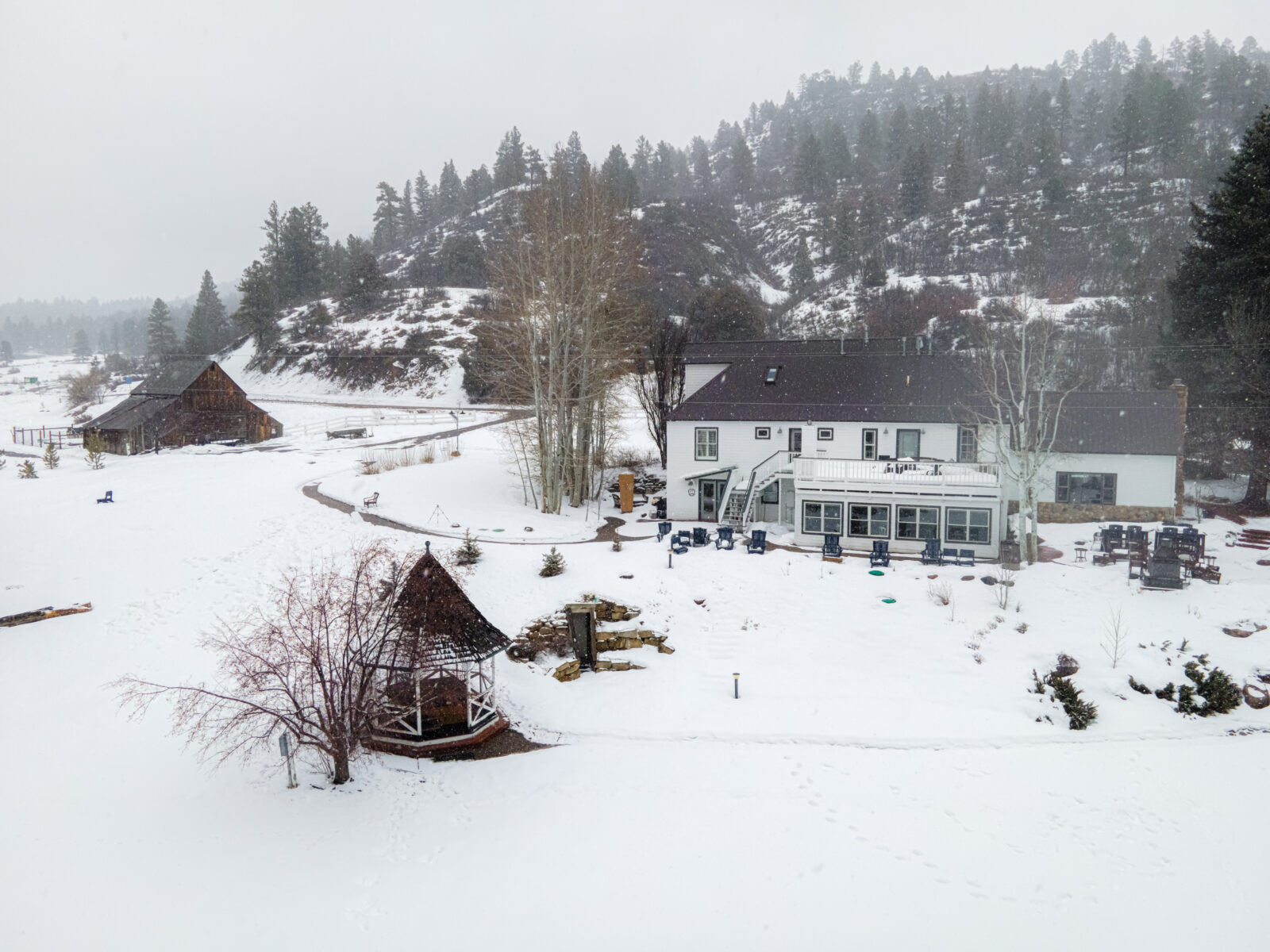 The exterior of our Durango Bed and Breakfast in winter. White house with gazebo, bare trees, snow.