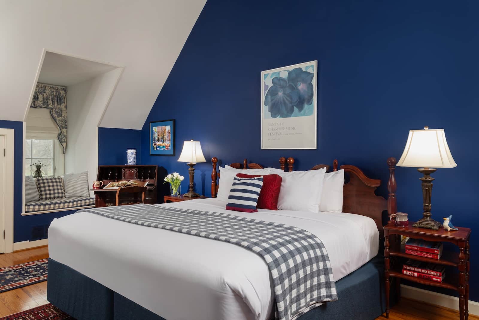 A bed against a navy wall with art at a Bed and Breakfast in Maryland.