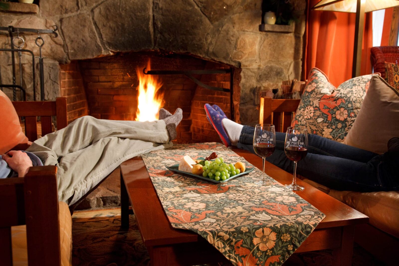 Couple relaxing by the fire with wine. Feet up on table, one of the best deep creek lake winter activities.