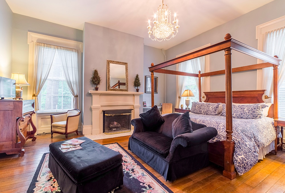 Sweet Old Fashioned guest room at Bourbon Manor, with a canopy bed, fireplace and sitting area