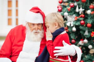 Boy whispers into Santa's ear. Santa will be at Koziar's until December 23.