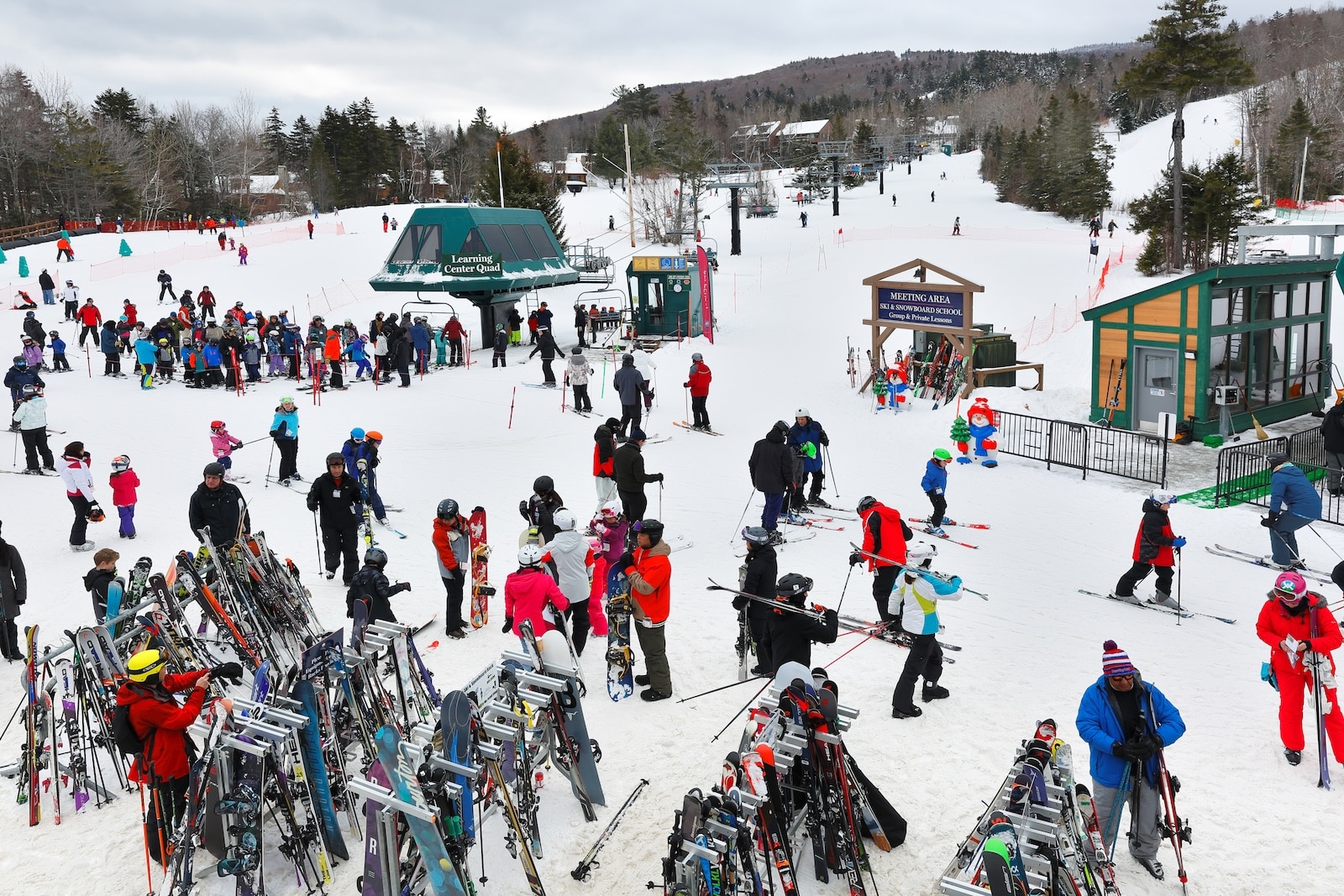 A crowd of people grabbing skis and mingling on a mountain of snow at Bretton Woods, one of the New Hampshire ski resorts for beginners.