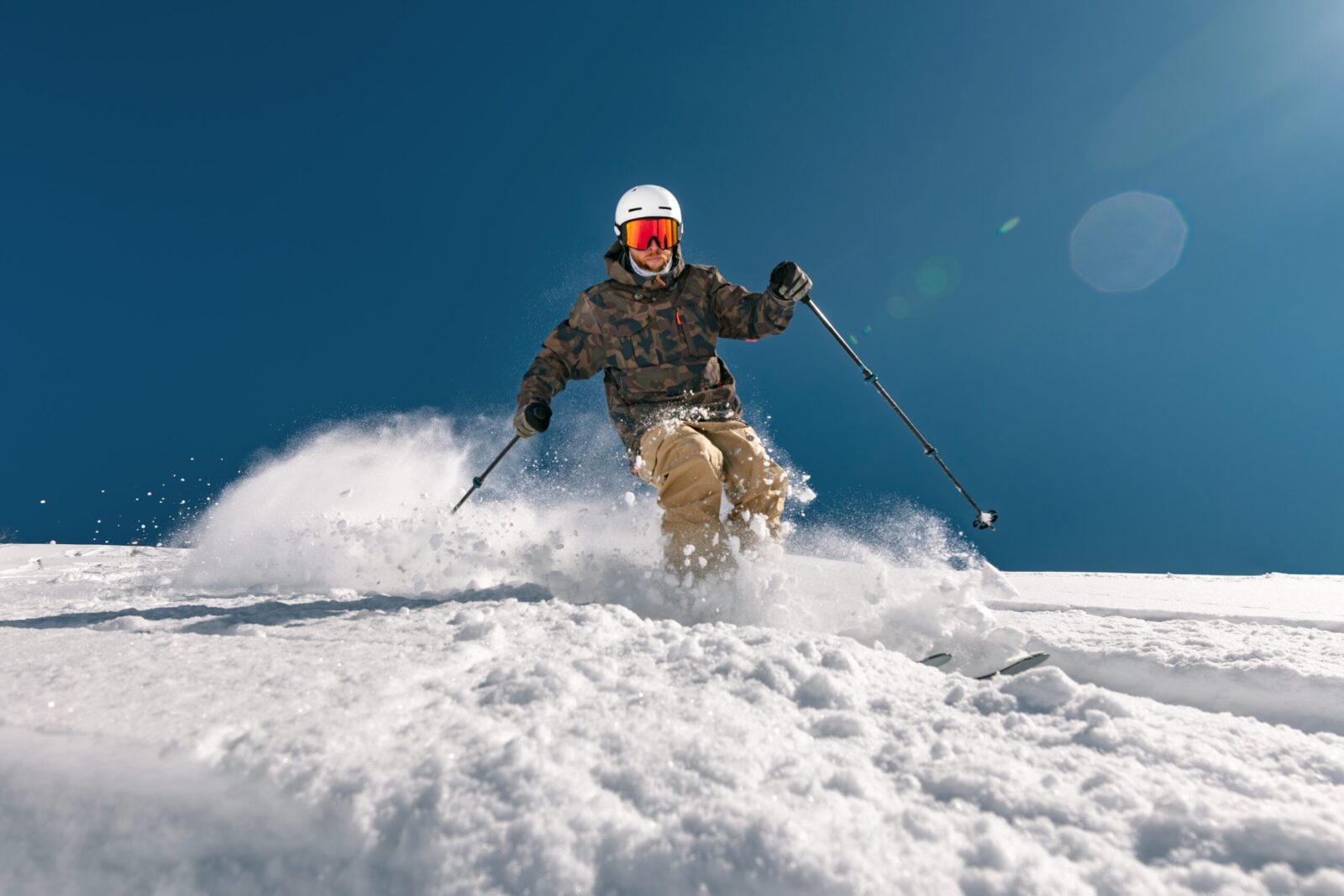 Front view of a skier skiing in deep snow and raising a cloud of snow behind him, bottom view. Purgatory Ski Resort